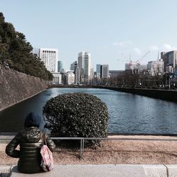 Rear view of woman sitting in front of river