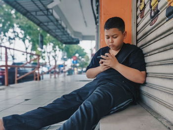 Young man using mobile phone while sitting on laptop