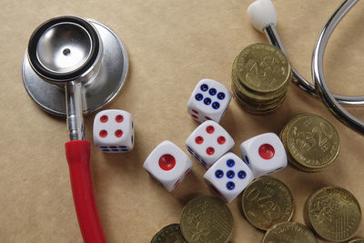 High angle view of stethoscope with dices and coins on brown table