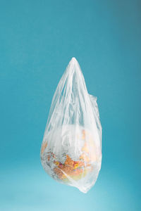 Close-up of globe in plastic bag against blue background