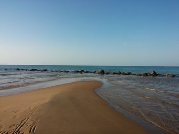 Scenic view of beach against clear blue sky