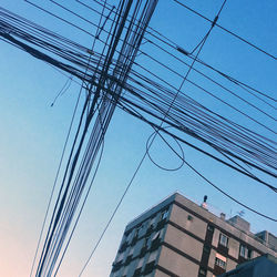 Low angle view of electricity pylon and buildings against sky