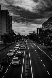 Traffic on city street by buildings against sky