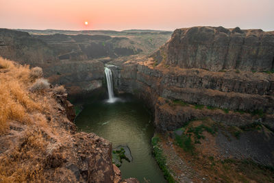 Scenic view of waterfall during sunset