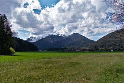 Scenic view of field by mountains against sky