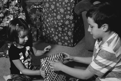 Siblings with christmas present at home