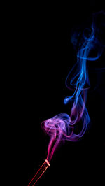 Close-up of burning incense sticks against black background