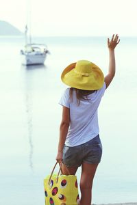 Woman with hand raised standing at beach