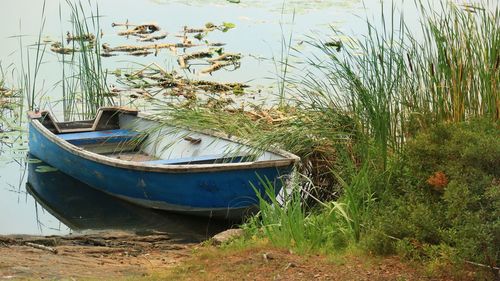 Boat moored on shore by lake against sky