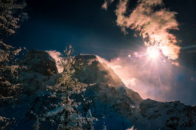 Firework display over mountains against sky during winter