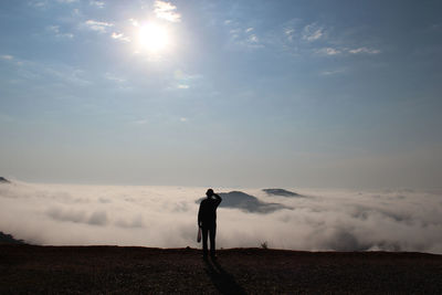 Rear view of man standing against cloudscape