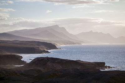 Scenic view of sea and mountains against sky