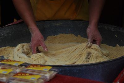 Midsection of chef preparing noodles at street market stall