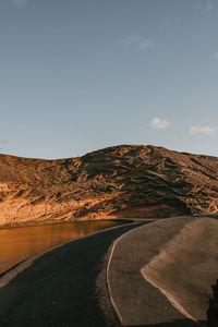 Road leading towards mountains against clear sky