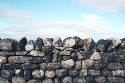 Stack of stones on rocks against sky