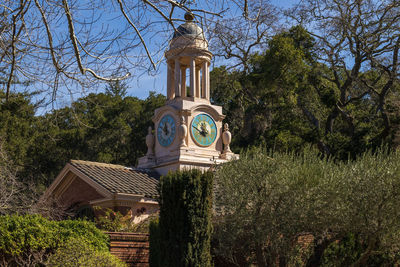 Clock tower amidst trees and building against sky