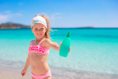 Portrait of young woman wearing bikini standing at beach