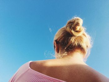 Low angle view of woman against blue sky