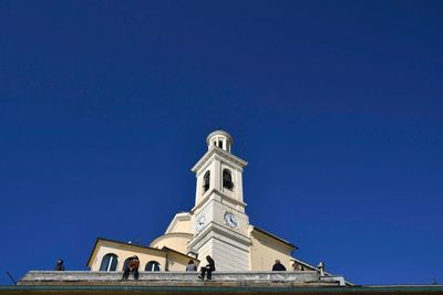 Low angle view of the churc of st anthony against blue sky and people relaxing at sun, boccadasse