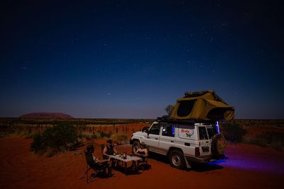 Cars on illuminated land against sky at night