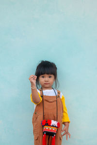 Portrait of cute baby girl standing against wall