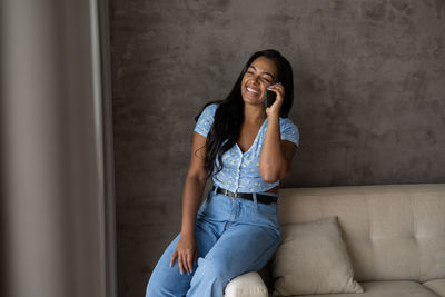 Young black woman working at home with smartphone on her couch in the living room. home office 