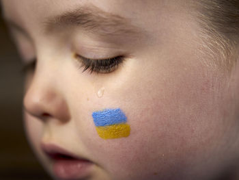 Child's crying with blue-yellow flag on cheek