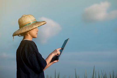 Midsection of woman holding mobile phone against sky