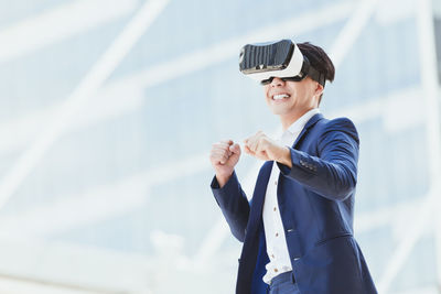 Businessman wearing virtual reality simulator against office building