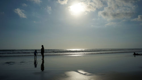 Silhouette people on beach against sky