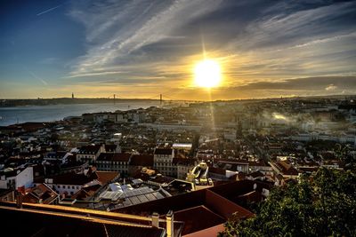 Lisbon cityscape by sea against sky during sunset