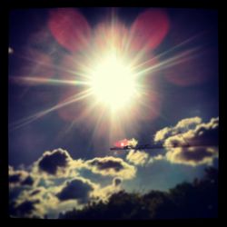 Low angle view of sun shining through clouds