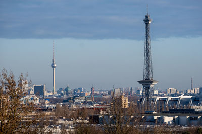 Communications tower in city against sky