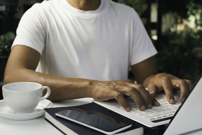 Midsection of man with coffee cup on table