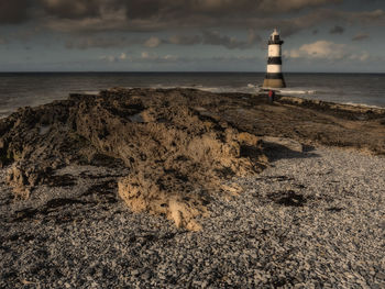 Lighthouse by sea against sky