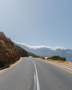 Road by mountains against clear sky