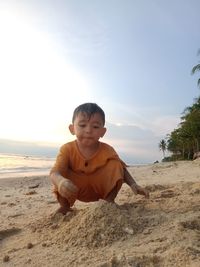 Portrait of boy sitting on sand at beach