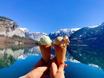 Hand holding ice cream cone against sky