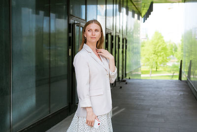 Smiling woman in casual clothes standing by the office. business woman