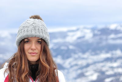 Portrait of beautiful woman in snow against sky