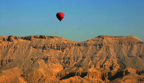 Hot air balloons flying in mountains against clear sky