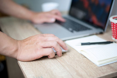 Midsection of man using laptop on table