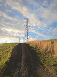 Electricity pylon on field against sky