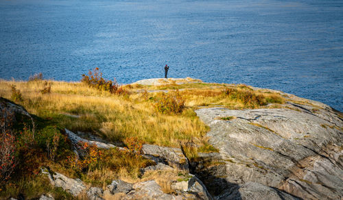 Man standing on rock formation against sea