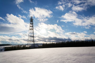 Communications tower on field against sky during winter