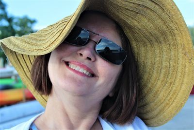 Close-up portrait of smiling woman wearing hat standing outdoors