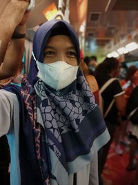 Close-up of a woman wearing a mask is standing on the bus