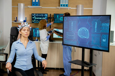 Rear view of woman using digital tablet while sitting on table