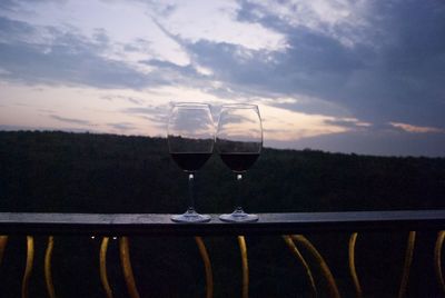 Close-up of wine glass against sunset sky