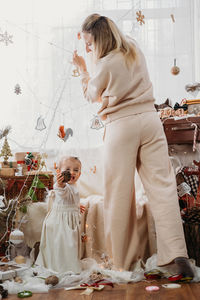 Full length of mother and daughter against christmas decoration at home